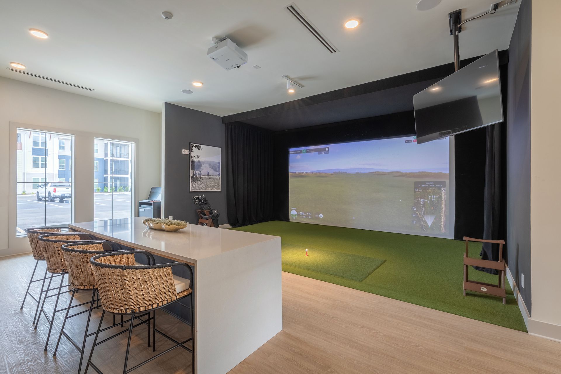 Indoor golf simulator room with a bar and chairs.