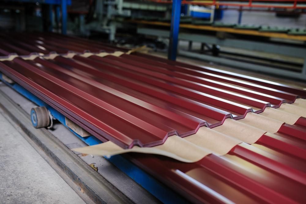 A Row of Red Corrugated Metal Sheets Sitting on Top of A Conveyor Belt — Howard Hardware and Building Supplies in Howard, QLD