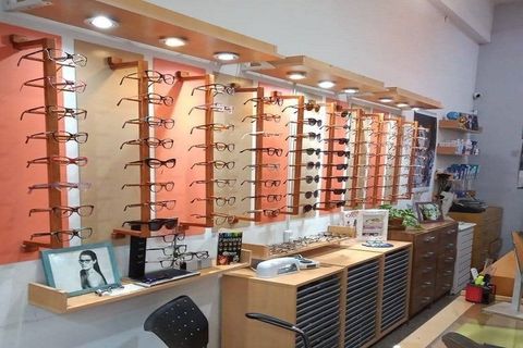 Exhibición de una óptica con filas de monturas en estantes y un mostrador en primer plano.