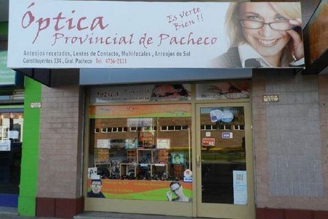 Fachada de la Óptica Provincial de Pacheco con un gran letrero de gafas y un escaparate de cristal.