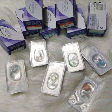 Surtido de blísteres y cajas de lentes de contacto sobre una superficie blanca y esponjosa.