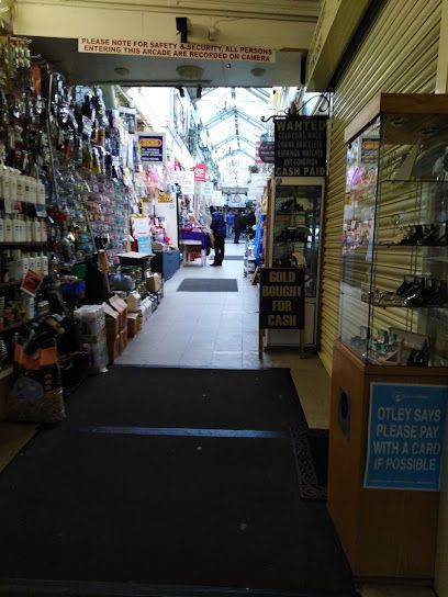 A covered shopping arcade with narrow aisles, displaying various goods in glass cases and on shelves under skylights.