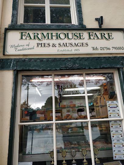 Storefront for Farmhouse Fare, featuring a sign for pies and sausages, a window display of awards, and a phone number.