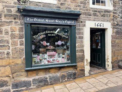 The Oldest Sweet Shop in England, a stone storefront with a display window and a green door numbered 66.