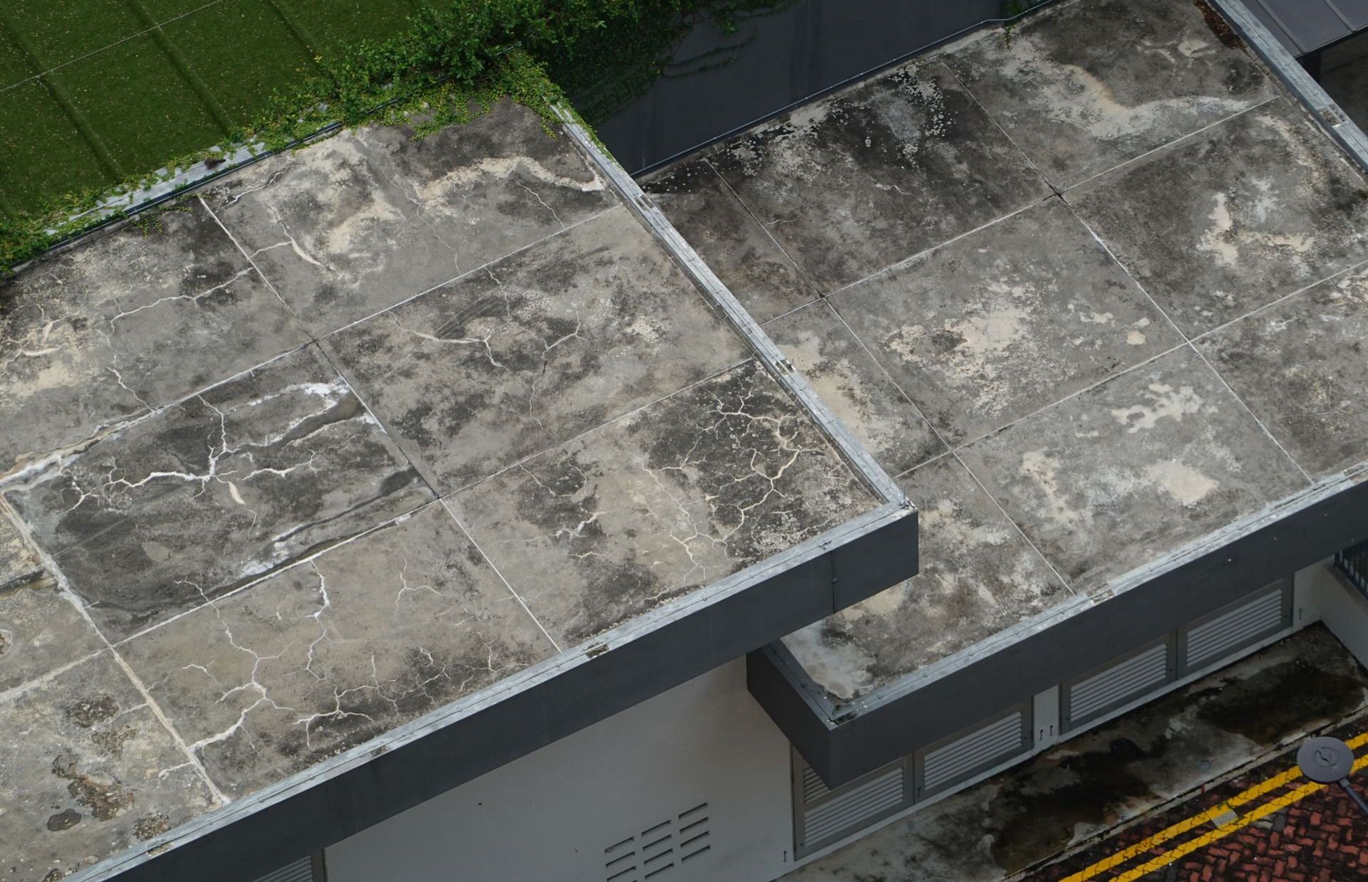 Aerial view of two flat rooftops with weathered gray tiles and dark edging