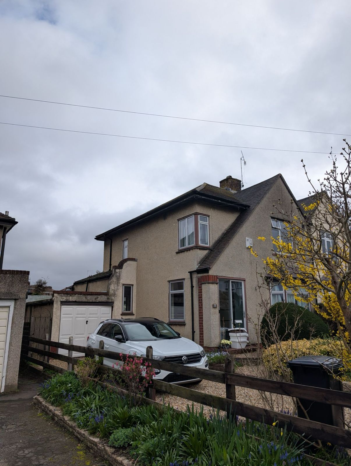 House with a parked car in a front yard on a cloudy day