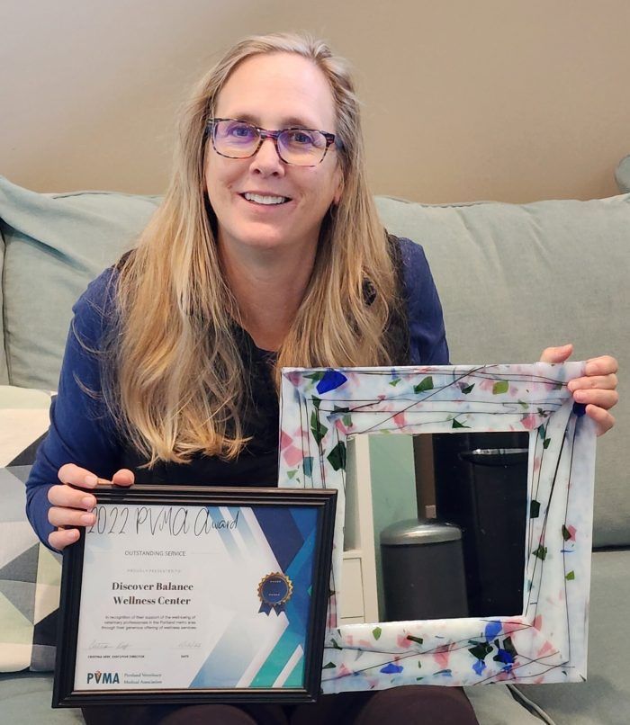 A woman is sitting on a couch holding a certificate and a picture frame