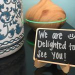 A sign that says `` we are delighted to see you '' is sitting on a table next to a vase.