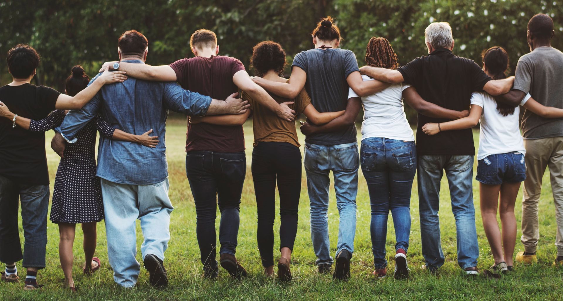 A group of people are standing in a row with their arms around each other.