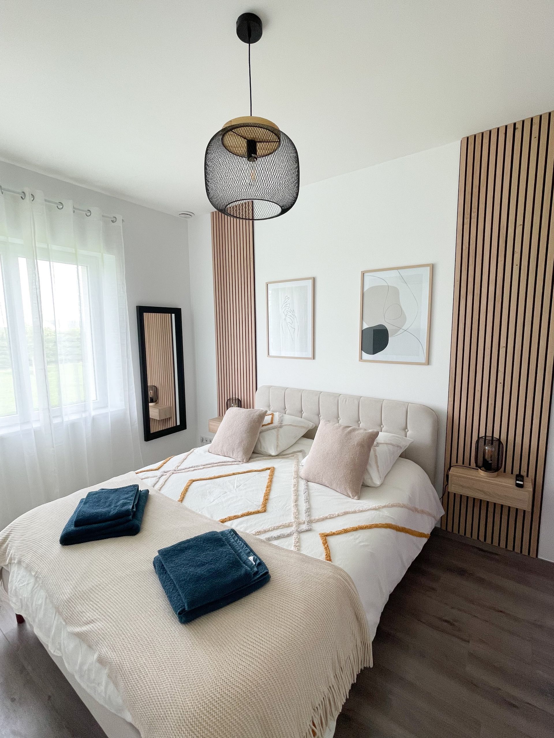 Une chambre avec un lit, un miroir, une table de nuit et une fenêtre.