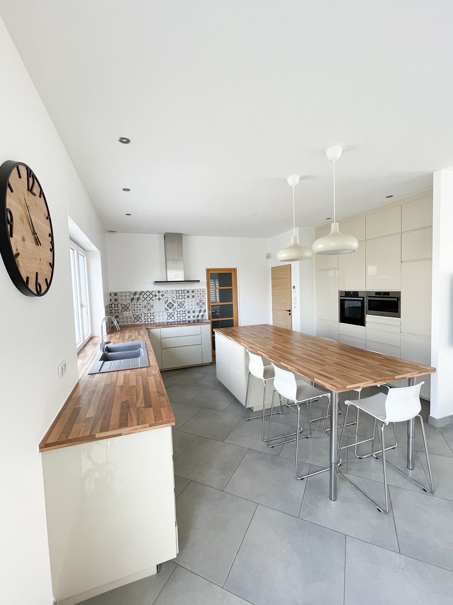 Une cuisine avec une grande table et des chaises en bois et une horloge au mur.