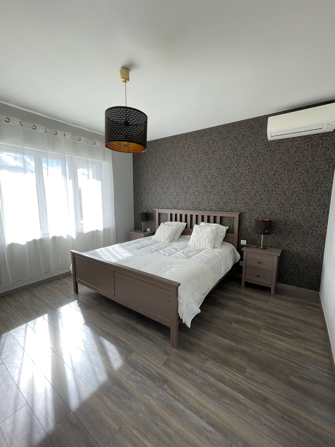 Une chambre avec un lit, des tables de nuit et un ventilateur de plafond.