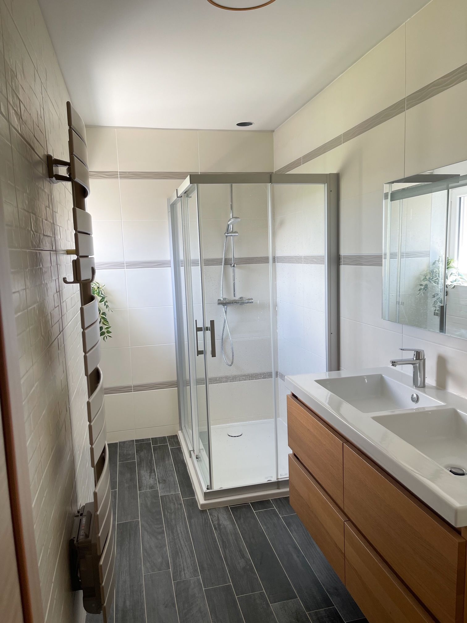 Une salle de bain avec deux lavabos, une douche et un miroir.