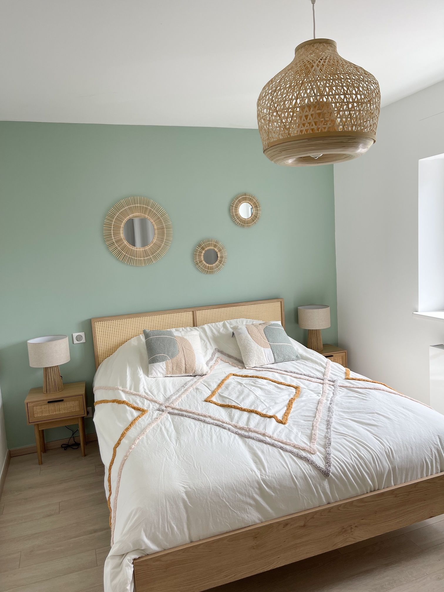 Une chambre avec un lit, des tables de nuit, des lampes et un mur végétal.