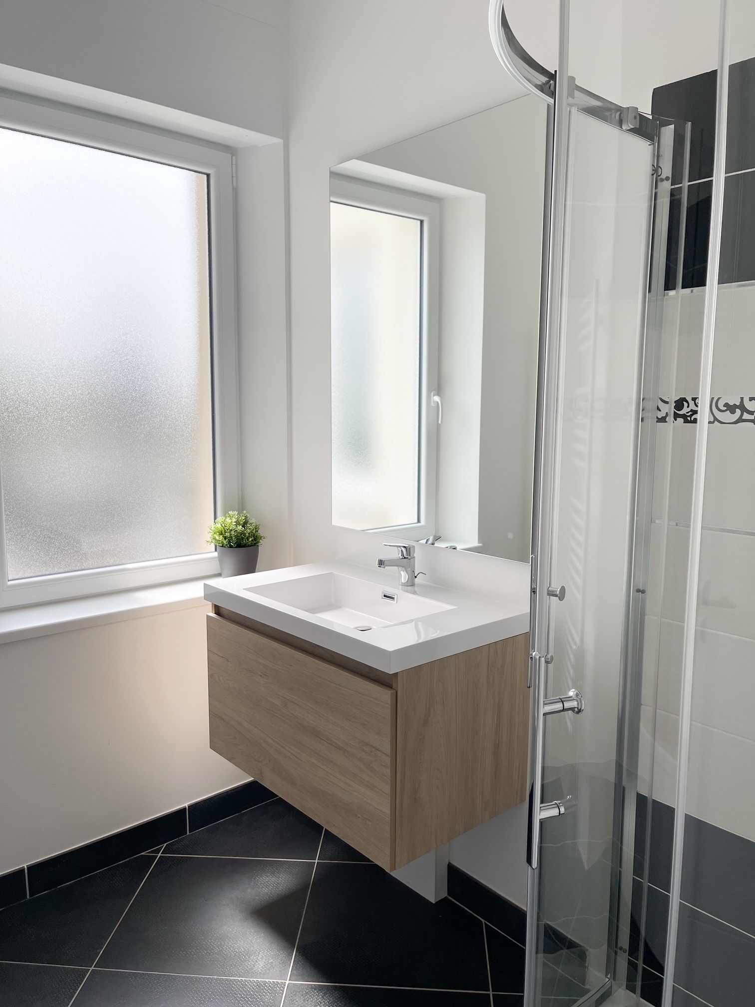 Une salle de bain avec lavabo, miroir et douche.
