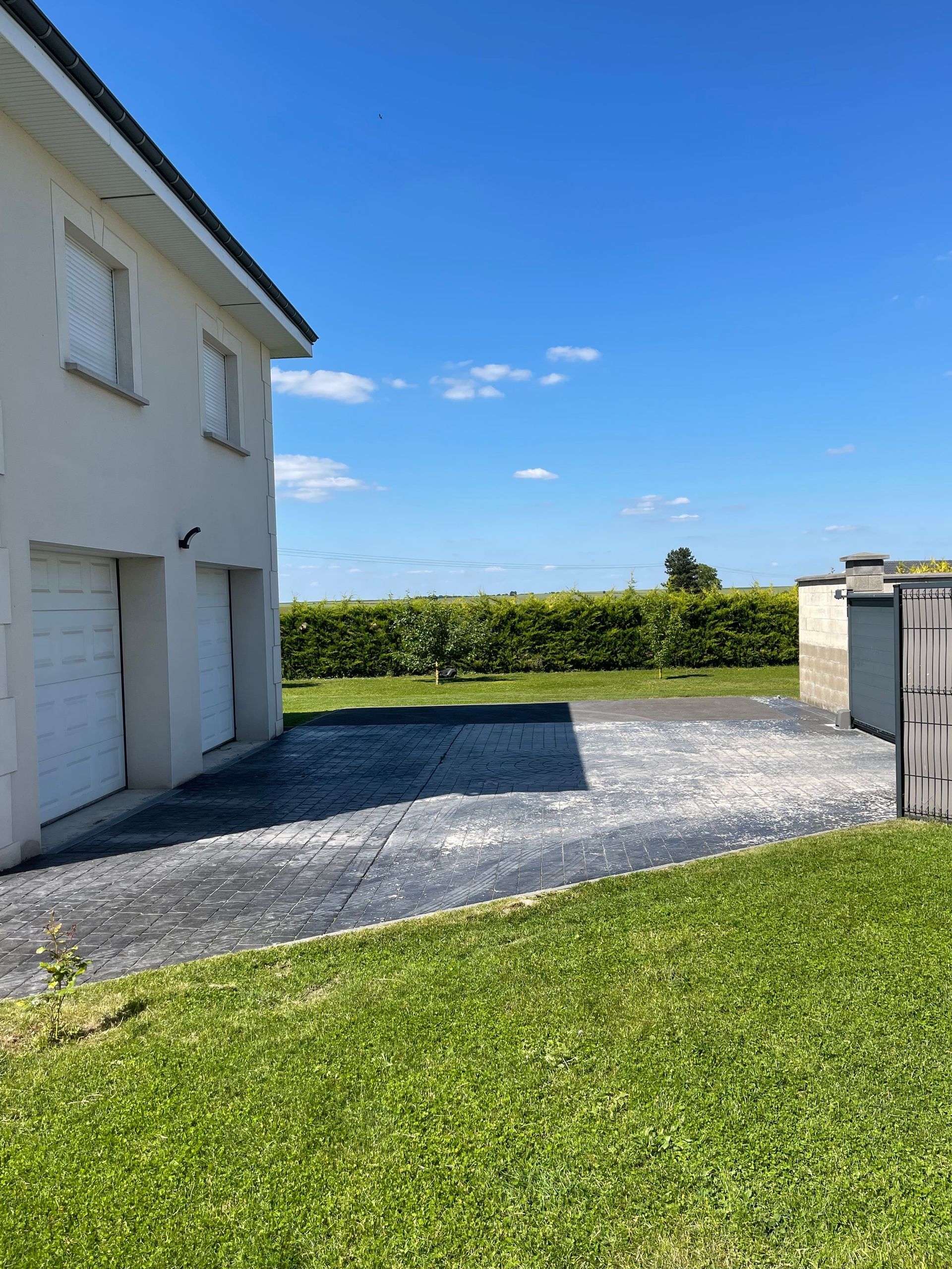 Une maison avec deux garages et une allée devant.