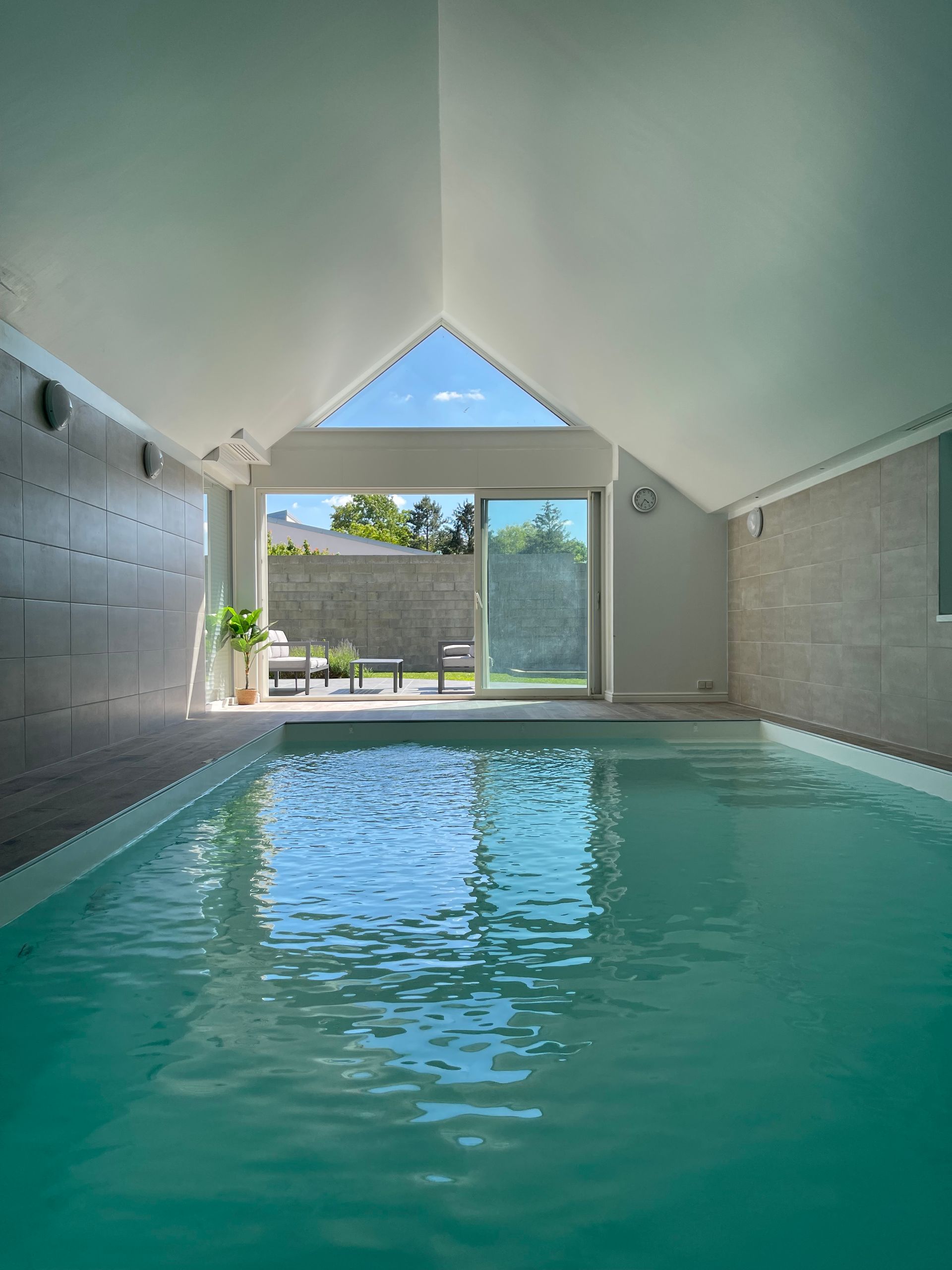 Une grande piscine intérieure avec un plafond voûté et une grande fenêtre.