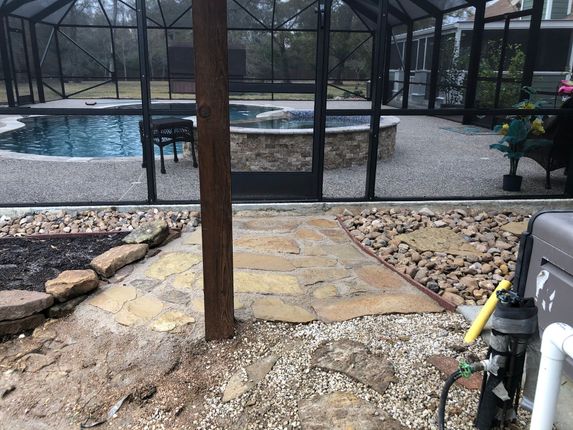 Pool area enclosed by screen, with flagstone path, river rock, pool, and spa.
