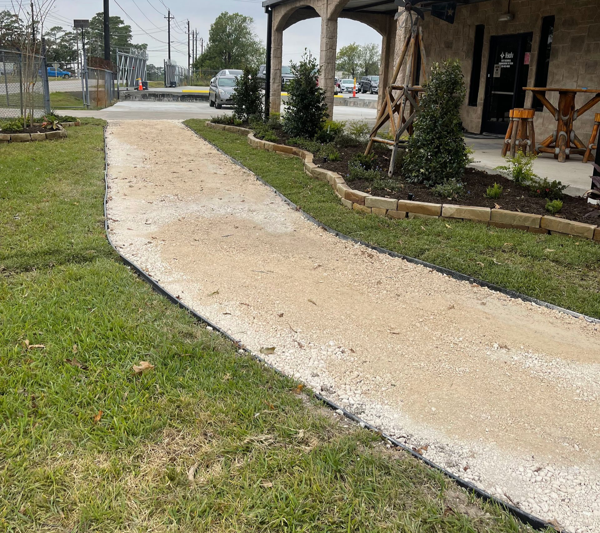 A gravel path winds through grass toward a building with an arched entrance.