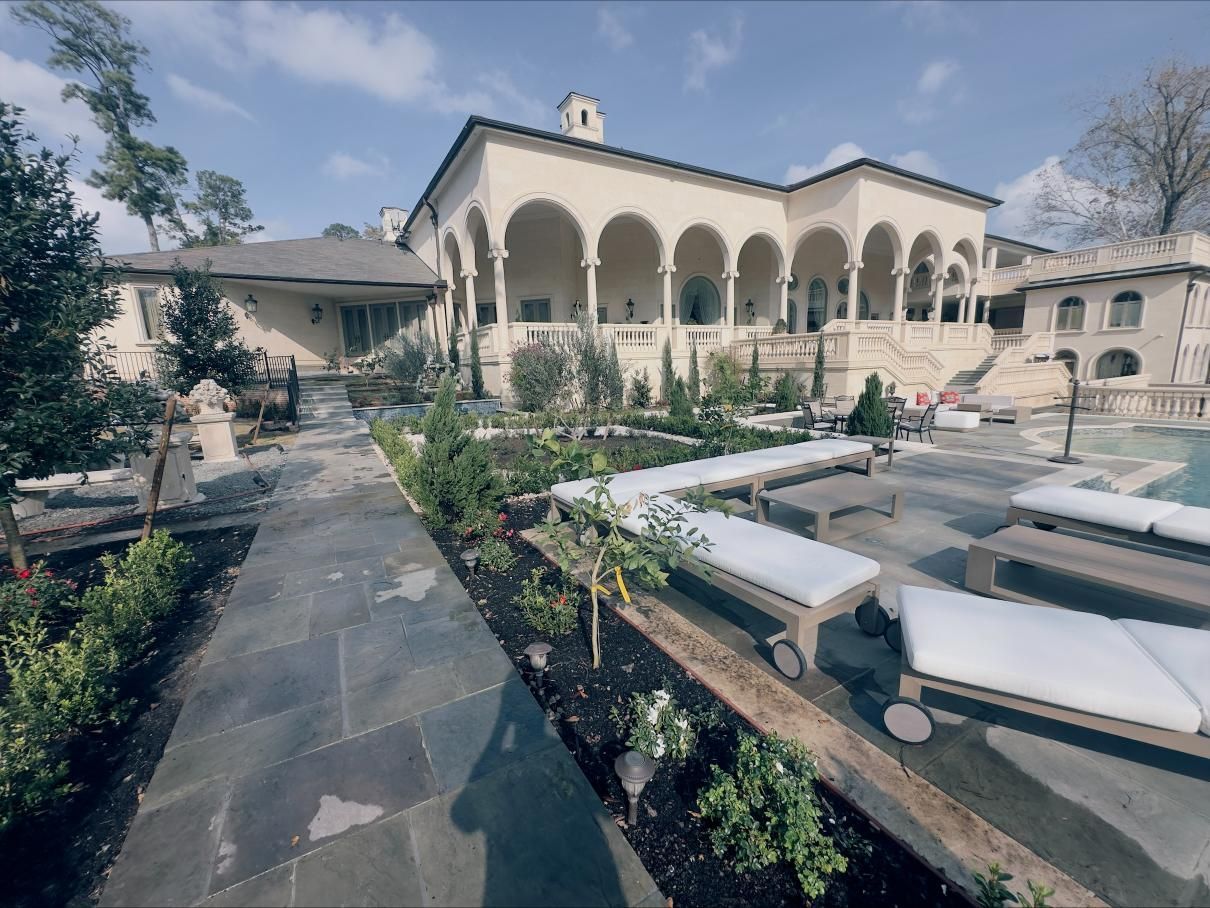 Stone walkway with flowerbeds. Brown rocks border dark soil with various green plants.