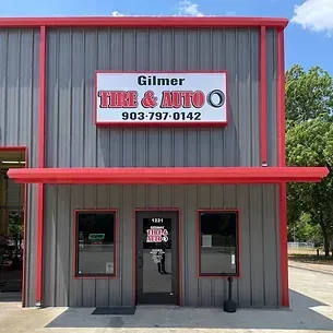 The front of a tire and auto shop with a red awning.