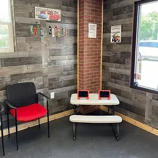 A waiting room with a table and chairs and two tablets on it.