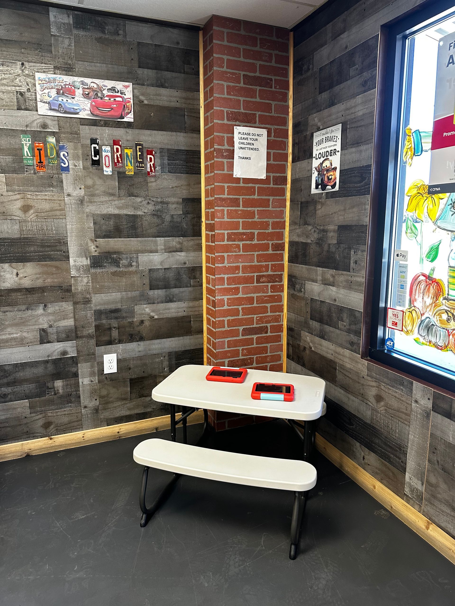 A room with a brick wall and a picnic table in the corner.