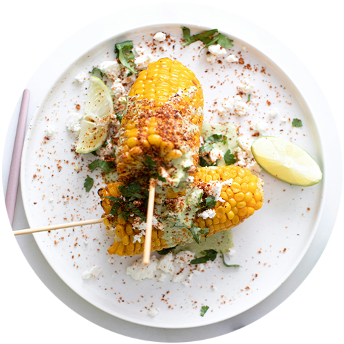 A white plate topped with corn on the cob on sticks.