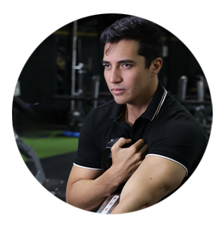 A man in a black shirt is sitting in a gym with his arms crossed
