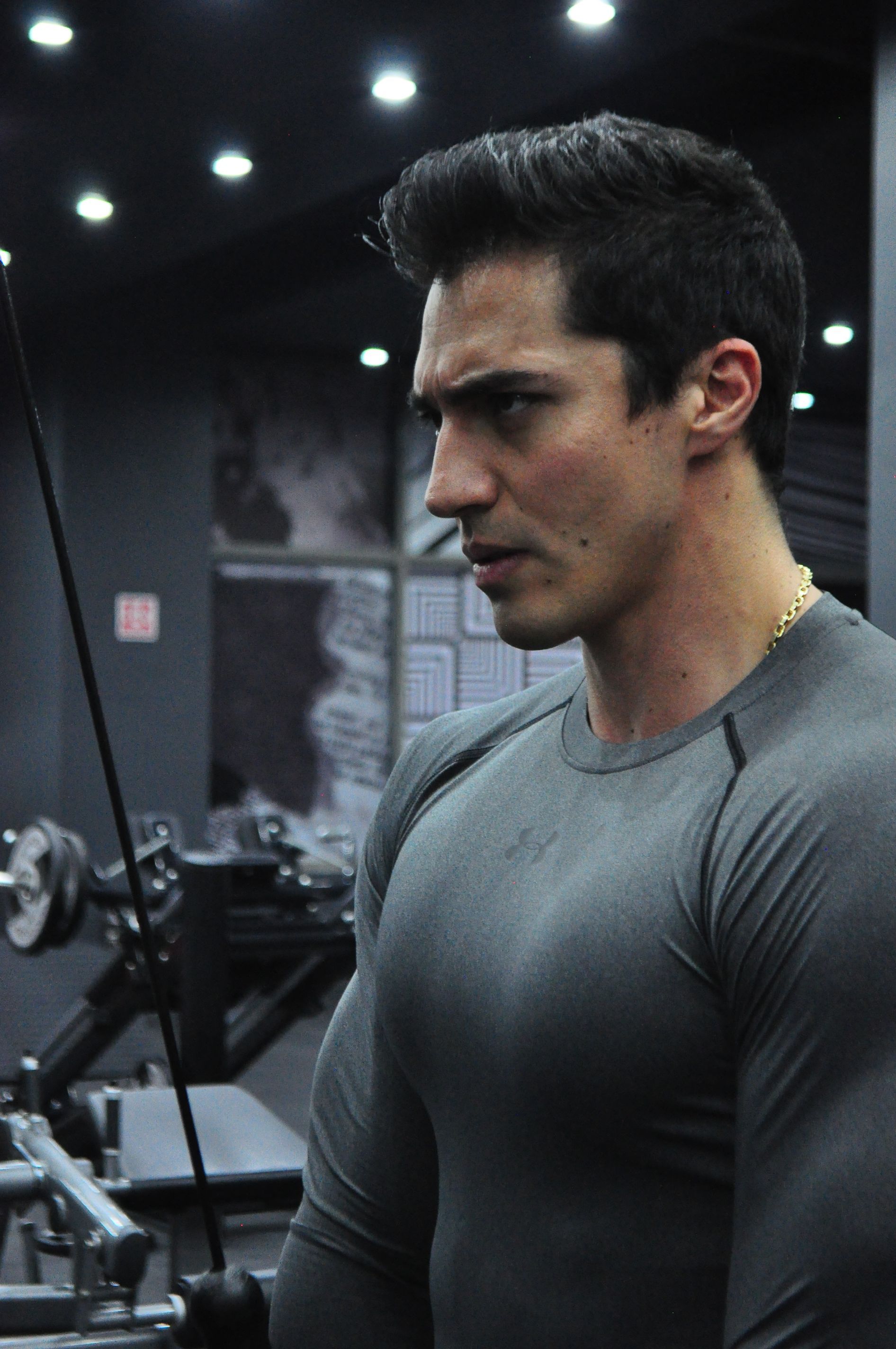 A man in a grey shirt is using a machine in a gym