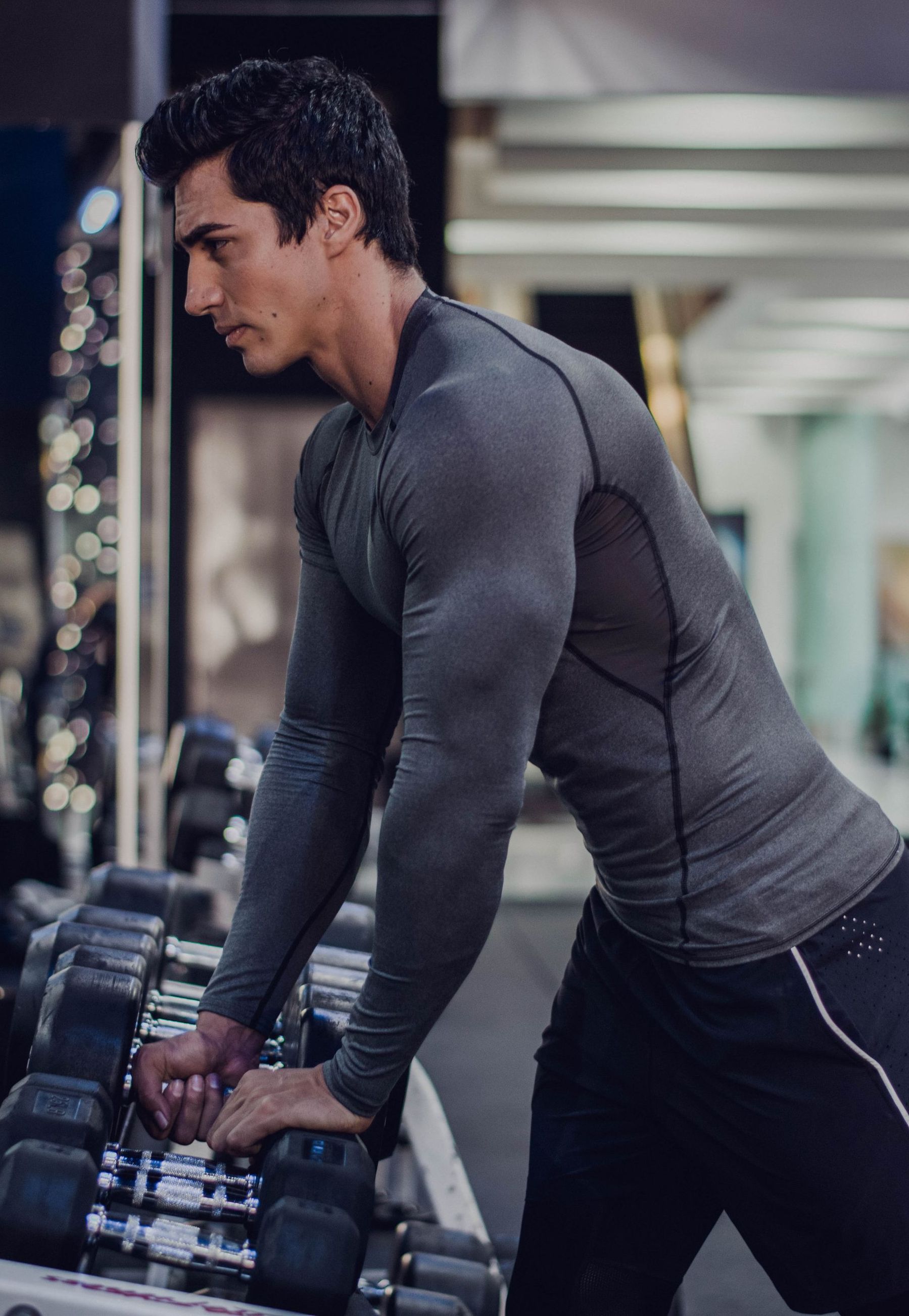 A man is lifting a dumbbell in a gym.