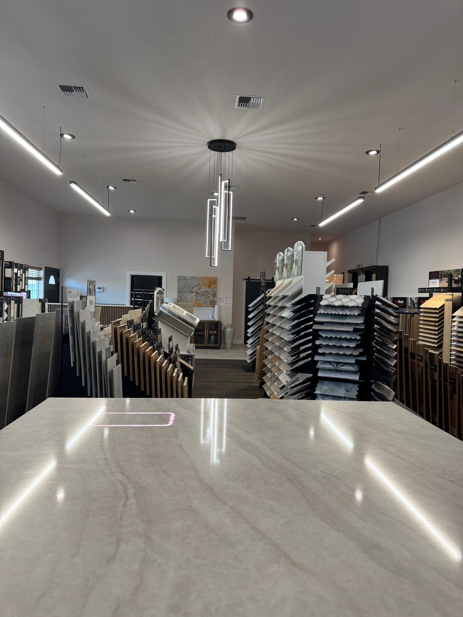 Inside a tile showroom: Marble countertop in foreground, displays of tile and stone in background.