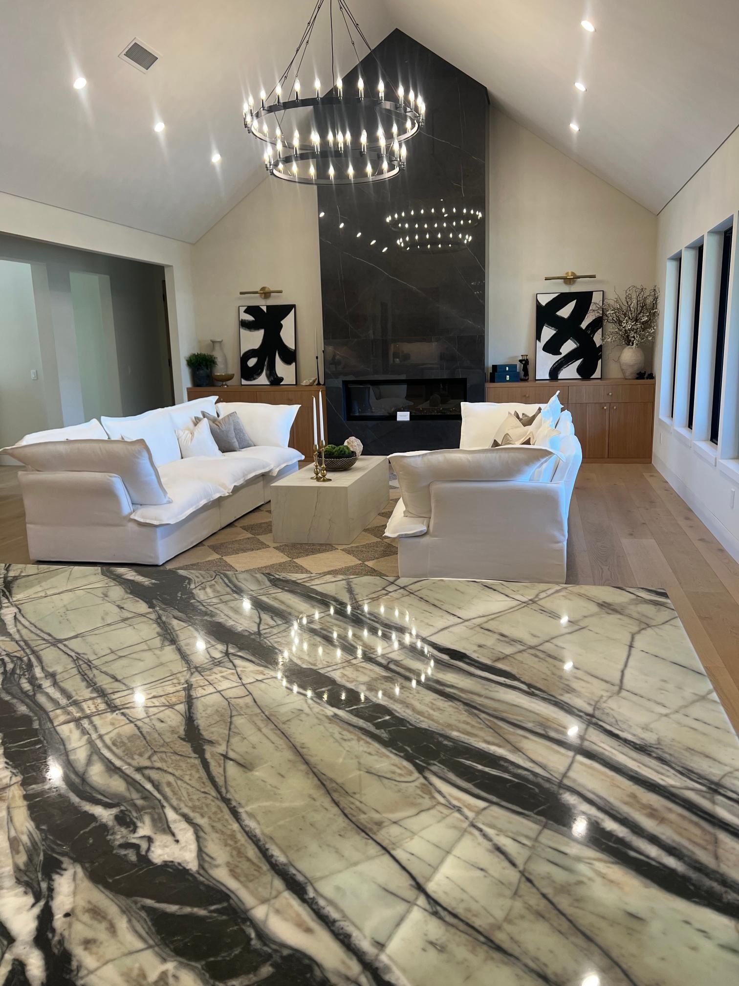 Luxurious living room with a large fireplace and chandelier, featuring a stone countertop in the foreground.