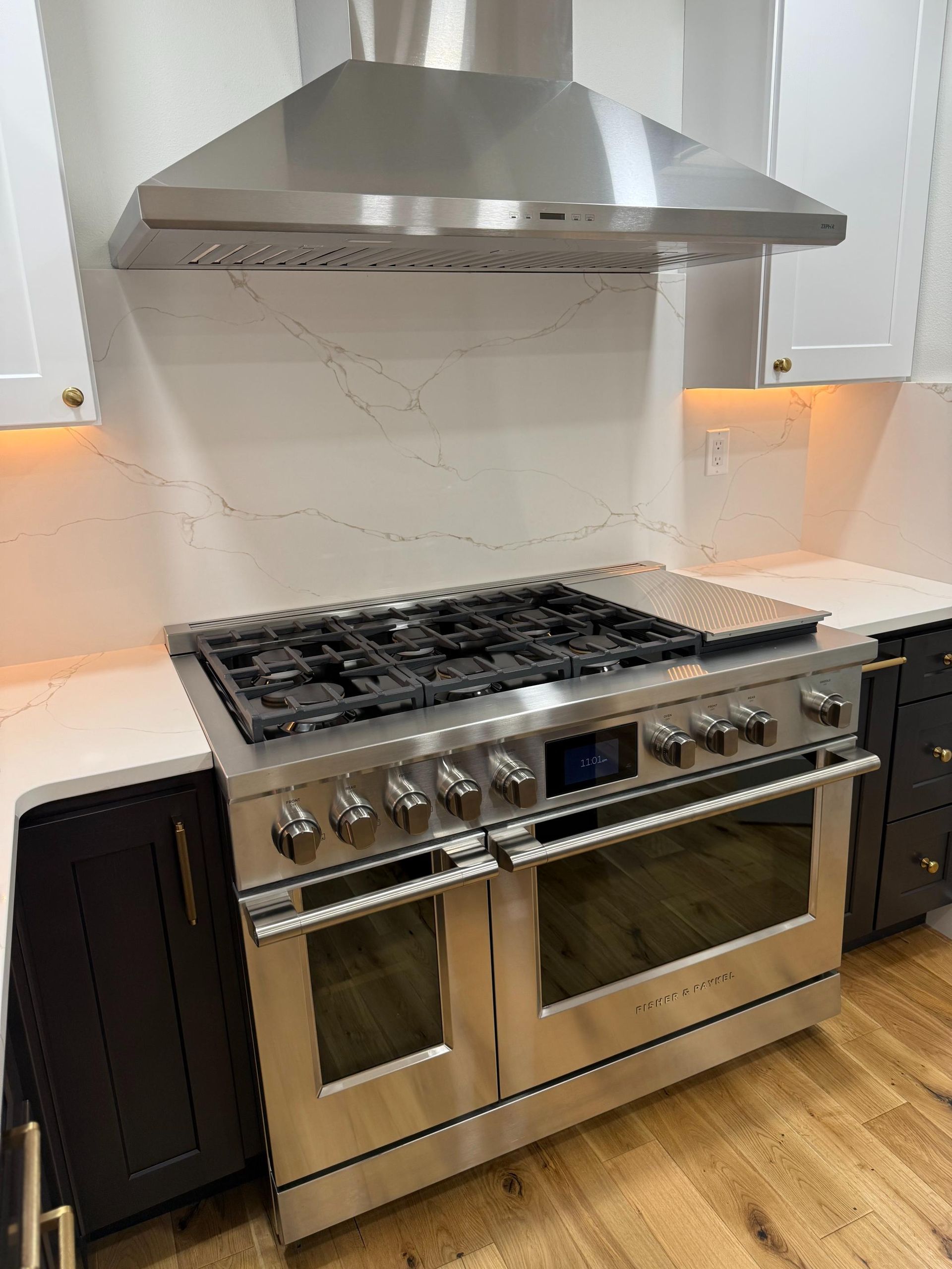 Stainless steel range with matching hood in a modern kitchen.