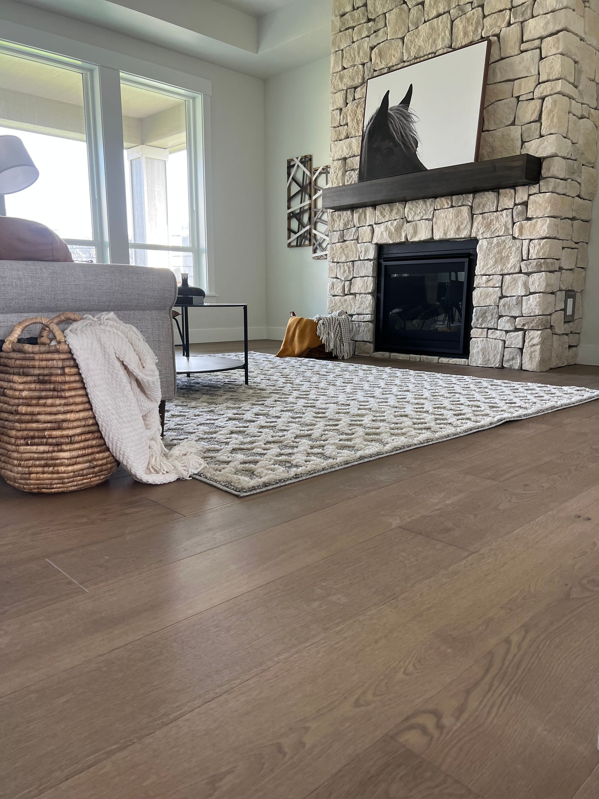 Modern bathroom with floating wood vanity, round mirror, and textured black wall.