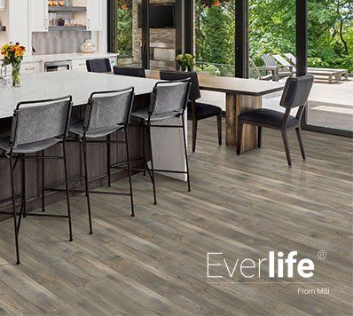 Kitchen with bar stools, dining table, and light brown wood flooring, with an Everlife logo.