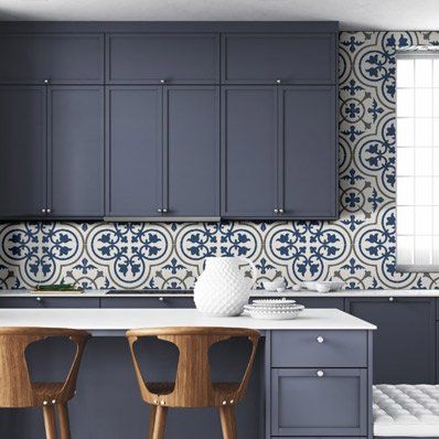 Blue kitchen with patterned backsplash, white countertop, and wooden stools.