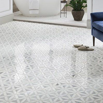 Bathroom floor with patterned white and gray tiles, a tub, and a blue chair.
