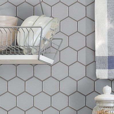 Gray hexagon tiles with dishes on a shelf and a dish towel, in a kitchen setting.