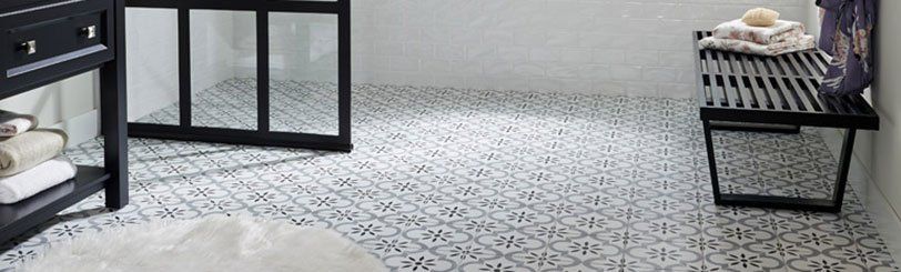 Bathroom with patterned tile floor, black furniture, white walls, and a fluffy rug.