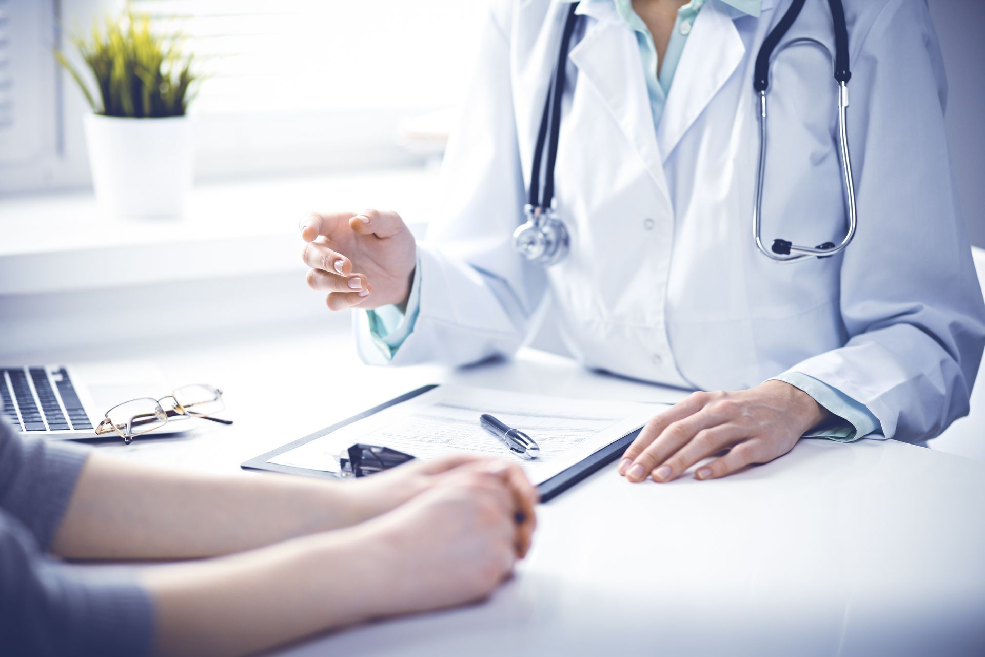 A doctor is sitting at a desk talking to a patient.