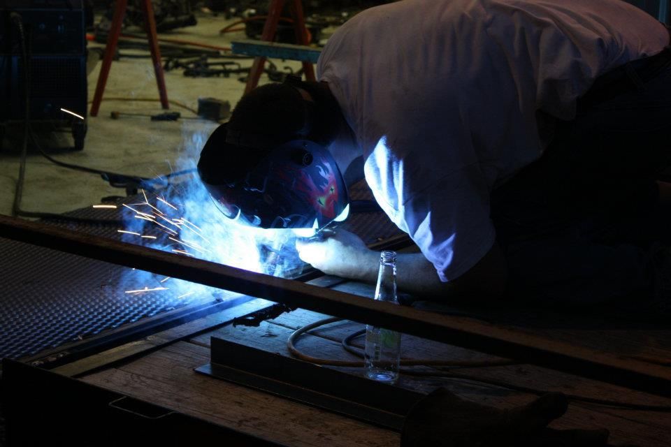 A man is welding a piece of metal in a dark room