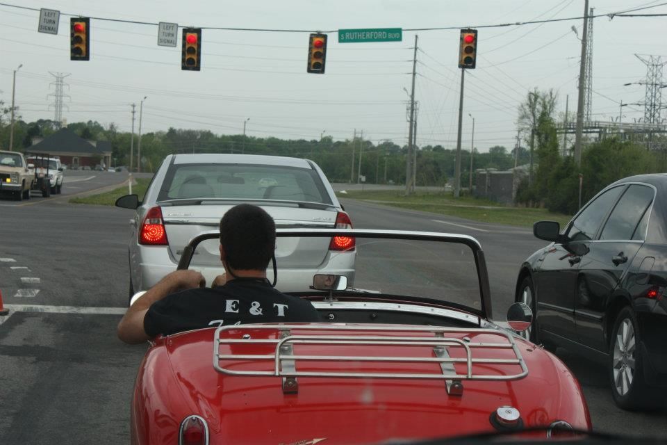 A man is driving a red sports car with the number 2t on his back