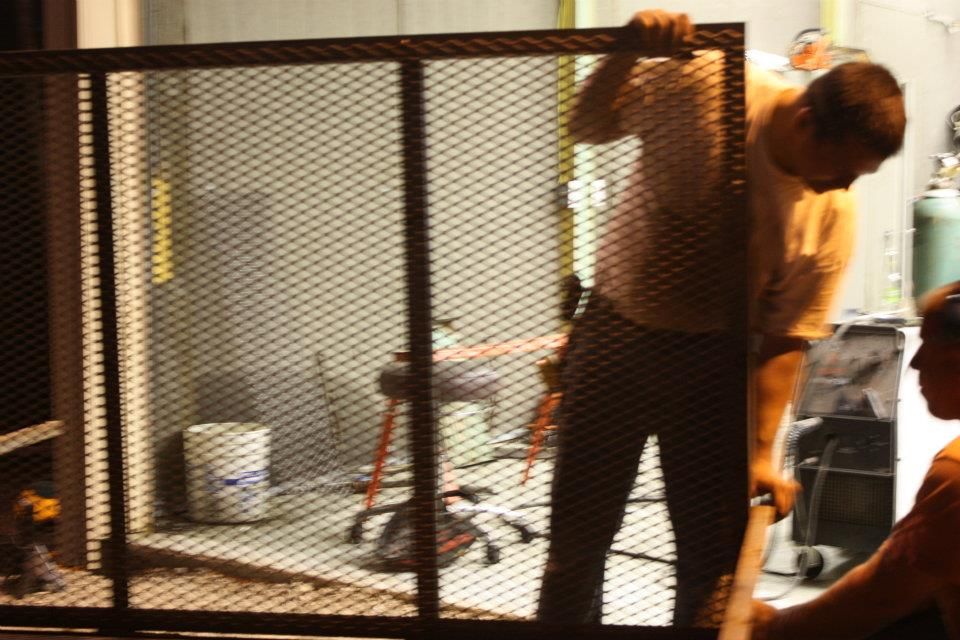 A man is standing behind a wire fence with a bucket in the background