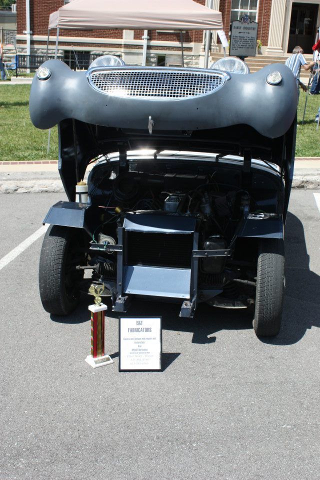 A car with the hood up and a trophy in front of it