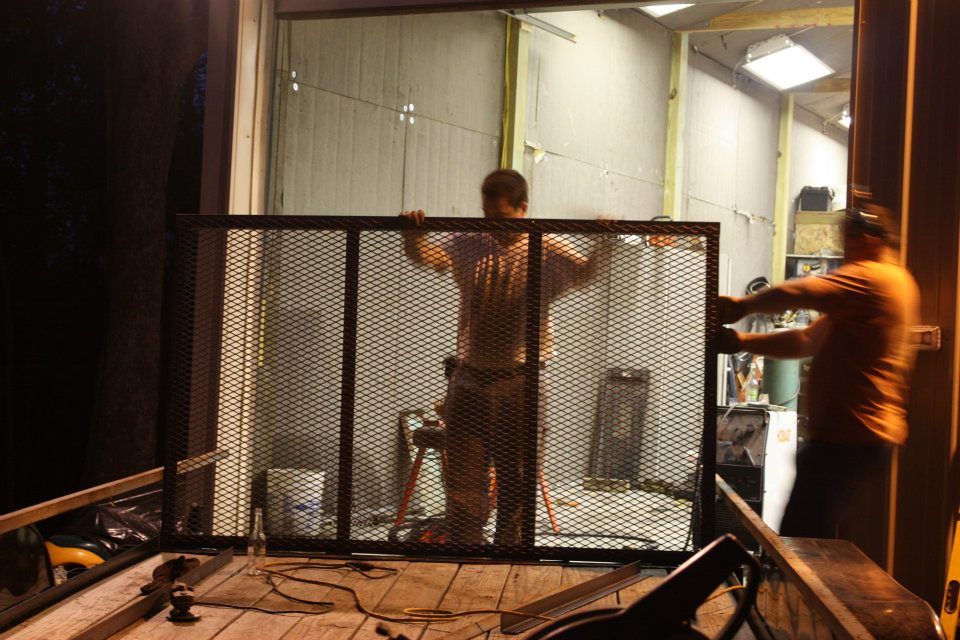 Two men are working on a fence at night.