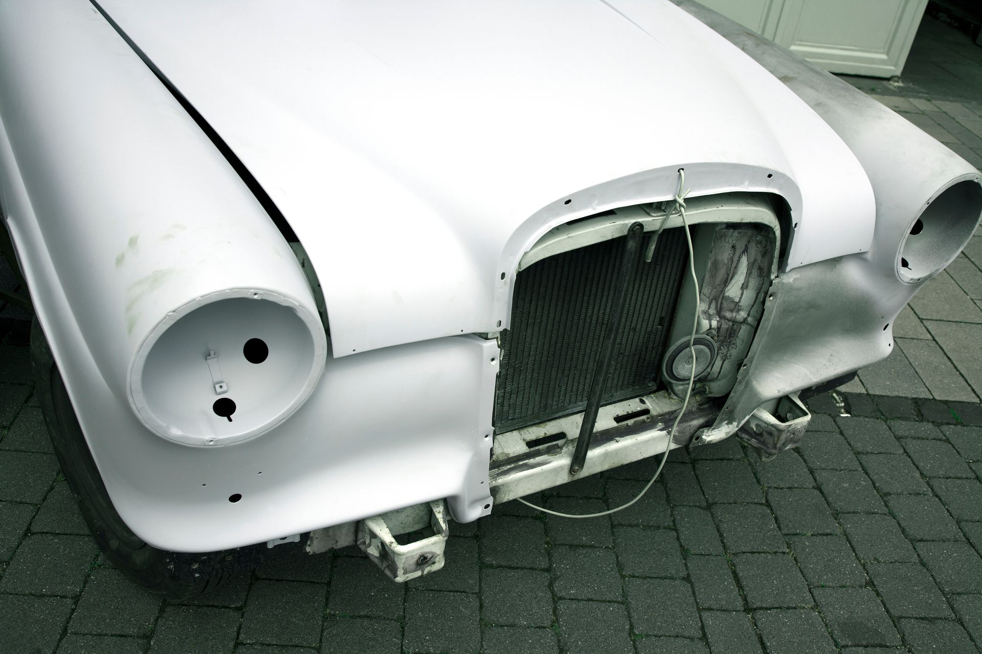 A white car is sitting on a brick driveway