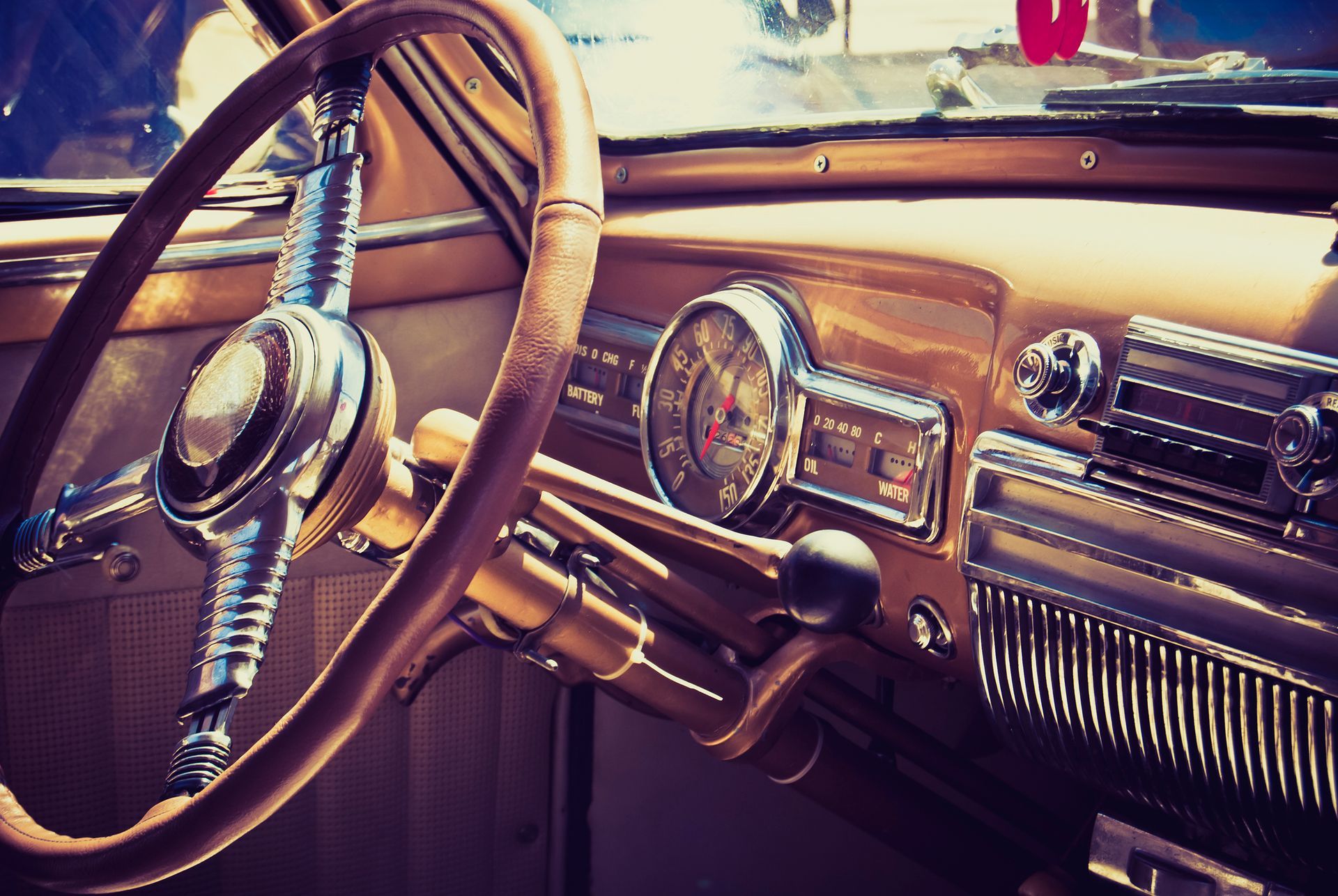 A close up of the steering wheel and dashboard of an old car