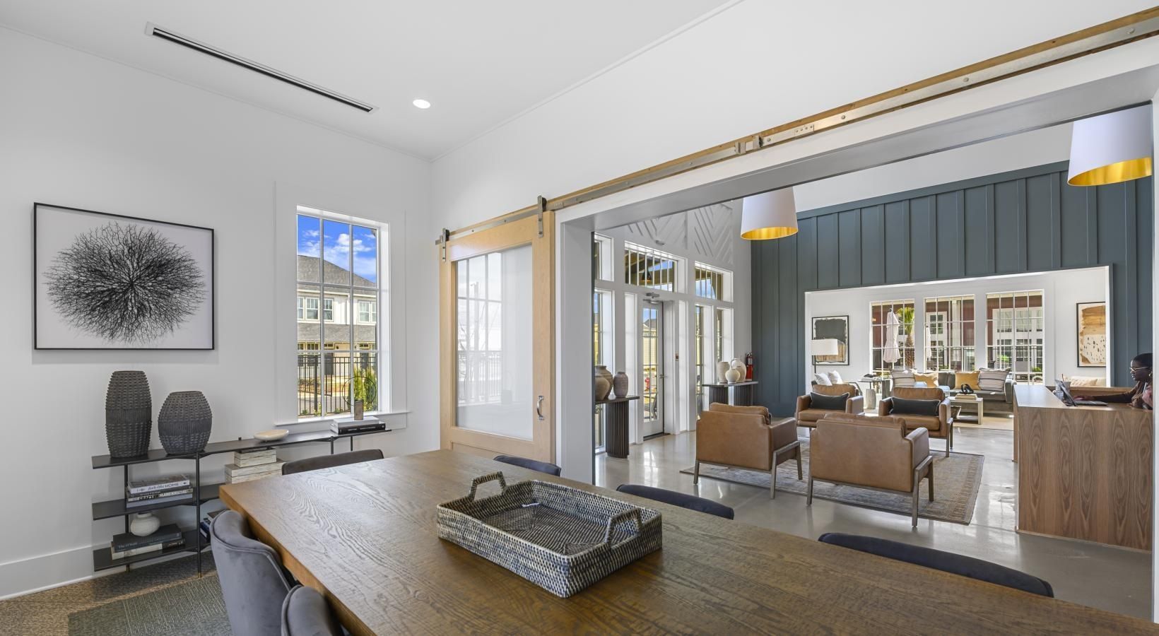 Interior community lounge with a long wooden table, sliding barn doors, and comfortable seating.