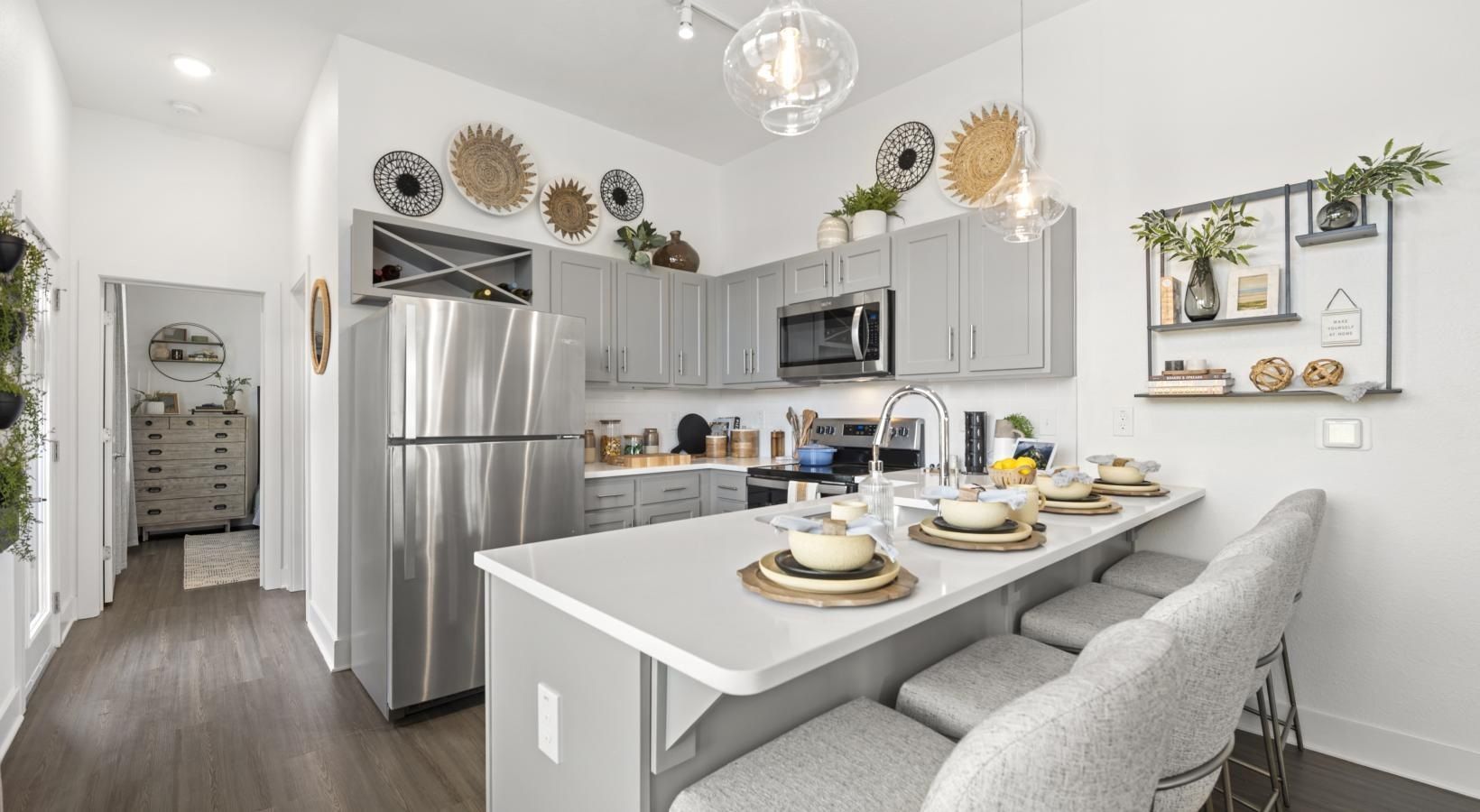 Modern gray kitchen with island, stainless steel appliances, and bar seating.
